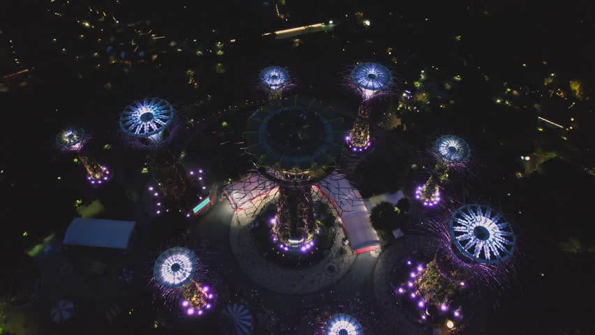 Aerial view to Cloud Forest and Flower Dome illuminated at the twilight. Famous hotel at the background. Gardens by the Bay, Singapore city in 4K.