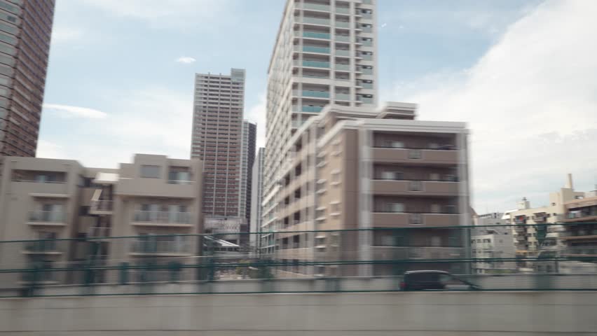 View of a suburban area from the window of the Shinkansen Bullet Train, Japan's high speed train. Beautiful blue sky with some cloud. Traveling in the direction of Tokyo. 