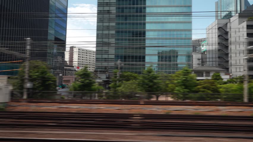 View from the window of the Shinkansen Bullet Train, Japan's high speed train. Pulling into the city. Traveling in the direction of Tokyo.  Royalty-Free Stock Footage #1103480719