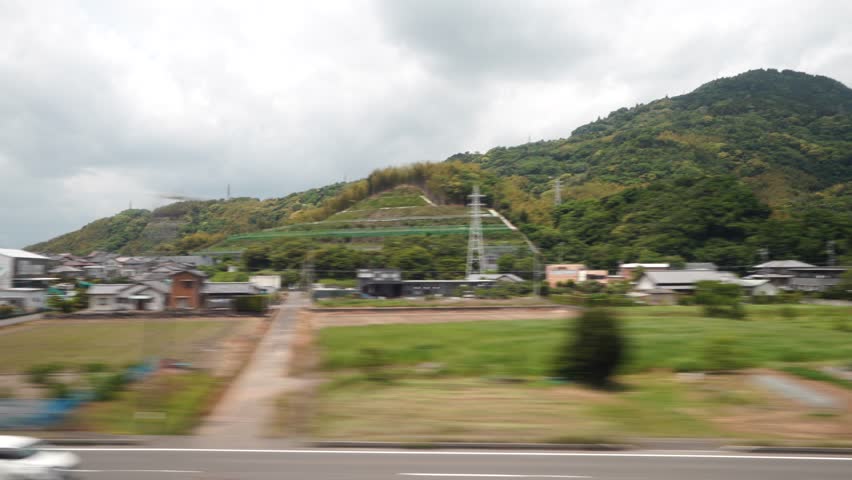 View of rural area from the window of the Shinkansen Bullet Train, Japan's high speed train. Traveling in the direction of Tokyo.  Royalty-Free Stock Footage #1103480741