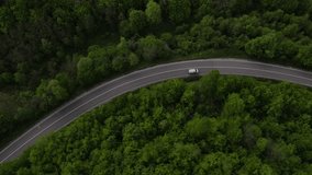 aerial drone footage of a curvy asphalt road on a mountain range during spring vehicle car driving along the winding road in Serbia surrounded by greenery and landscapes transport and travel concept