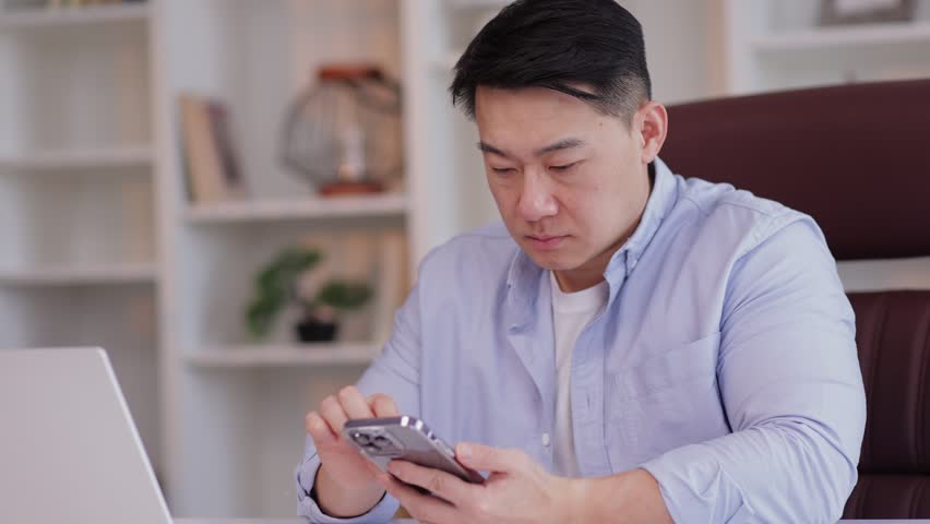 Upset asian business man in office using smart mobile phone failure. Cannot enter data no weak internet network. Male user frustrated by bad news signal service fail on smartphone app Royalty-Free Stock Footage #1103484499