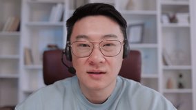 asian man wear headset making video call helpline from office, looking at camera, smiling, attending online chat, virtual conference. Video call head shot portrait