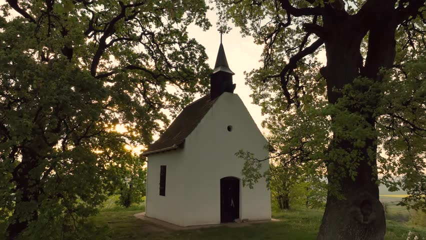 Small chapel under two trees at sunrise time in windy time. Actually this place name is Saint Orban chapel in Bataszek Hungary. The trees won the trees of Hungary prize. 