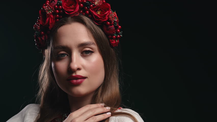 Charming ukrainian woman in ethnic costume, wreath on black studio background.