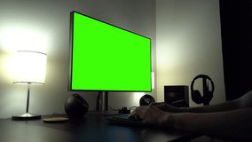 A man works on a desktop computer with a green screen - types on a keyboard - closeup