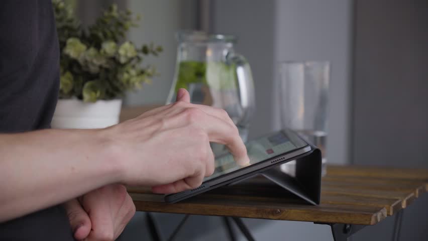 A man works on a tablet on a balcony - side closeup