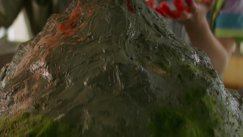 Portrait of father is helping his daughter to prepare a school science class volcano project, mixing vinegar and baking soda to imitate the eruption