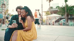 Close up of happy man and smiling woman watching video on smartphone. Close-up of a joyful young couple browsing photos on a mobile phone on urban city background