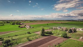 Enchanting aerial footage of a quaint village nestled in the lush, green Po Valley countryside during a spring sunset.