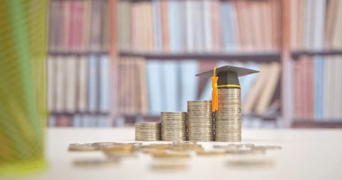 Tuition payment or tuition fee, expense for graduate study abroad program concept : Black graduation cap on stacks of coins, depicting fees charged by education institution for instruction or services Video de stock