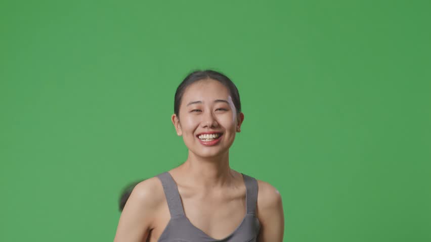 Close Up Of Asian Woman Wearing Sportswear And Running On Green Screen Background In The Studio
