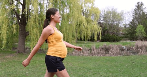 Prenatal workout pregnant woman walking outside in park living an active lifestyle during pregnancy. Daily walks during summer outdoor: film stockowy