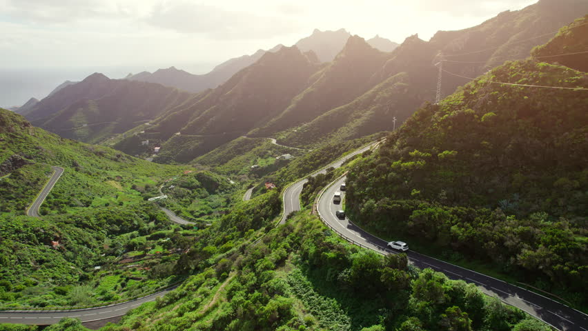 Aerial view of green volcanic landscape with serpentine road in northern part of Tenerife, Canary islands, Spain. Mountain road in Tenerife at sunset. Royalty-Free Stock Footage #1103510305