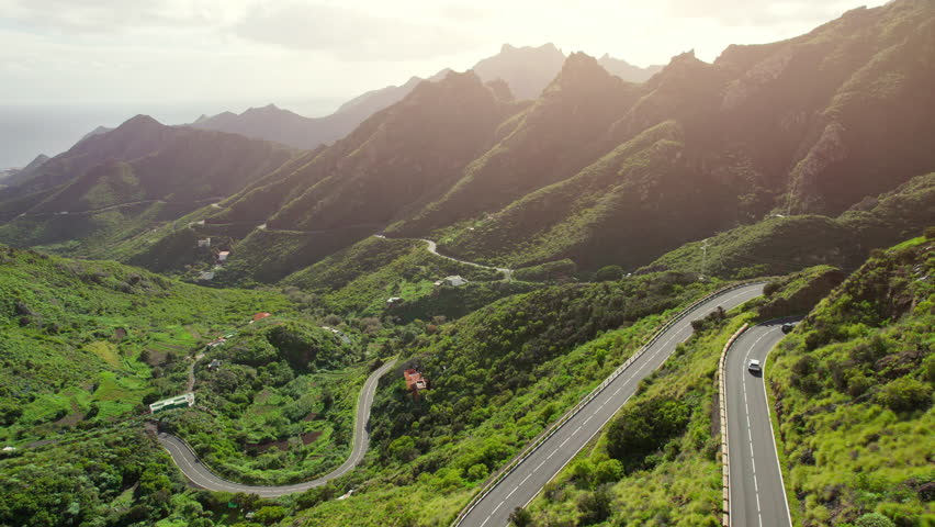 Aerial view of green volcanic landscape with serpentine road in northern part of Tenerife, Canary islands, Spain. Mountain road in Tenerife at sunset.