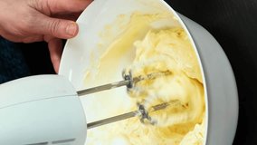 Process of making buttercream for cake. Vertical video. Baker mixing butter and sugar in bowl using electric mixer, cooking sweet pastry. Confectionery baking cake at home, preparing sweet cream