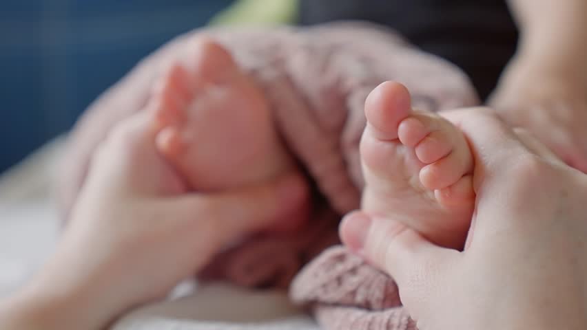 Mom doctor gives foot massage to her baby. happy family kid baby concept. Children massage: care and care of the doctor mother. Foot massage baby health: doctor mom help. baby foot massage dream