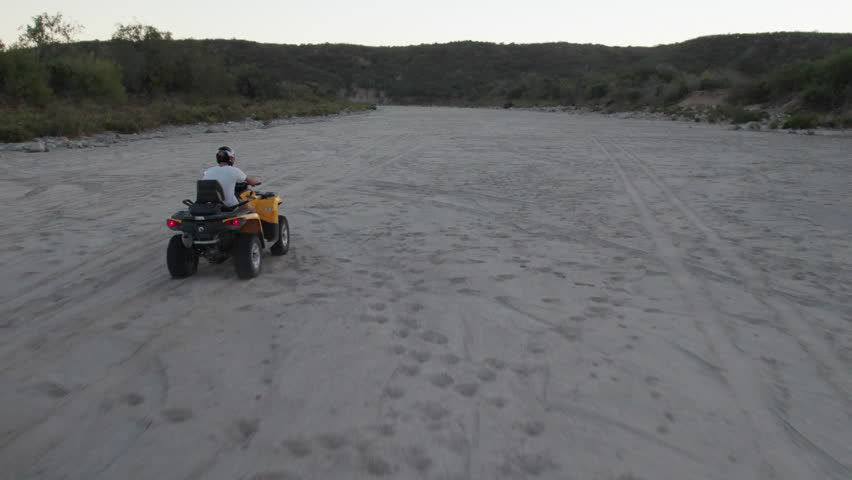 Man riding a motorcycle. Drone follow over dirt road in Los Cabos, Mexico