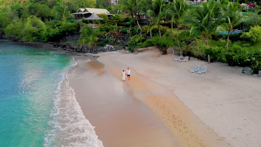 Saint Lucia or St Lucia tropical Island with the blue turqouse colored ocean at sunset. A couple of men and women walking on the beach Royalty-Free Stock Footage #1103521579
