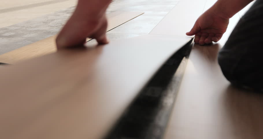 Man kneeling and installing wood laminate floor in a home. Closeup on male hands. | Shutterstock HD Video #1103522677