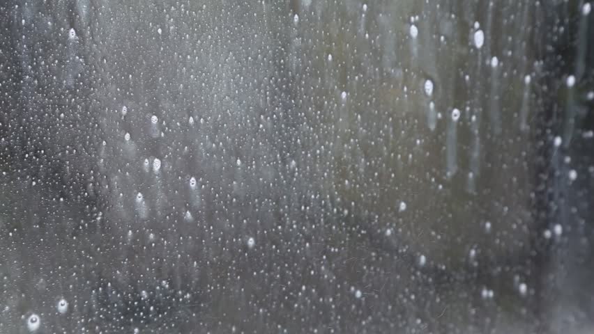 water with cleaning products slides on a glass in broad daylight. Cleaning windows in the house.