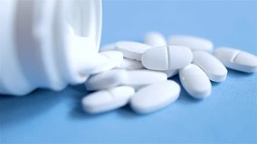 Tablets, calcium and magnesium supplementation to strengthen bones, video of a bunch of pills isolated on blue background