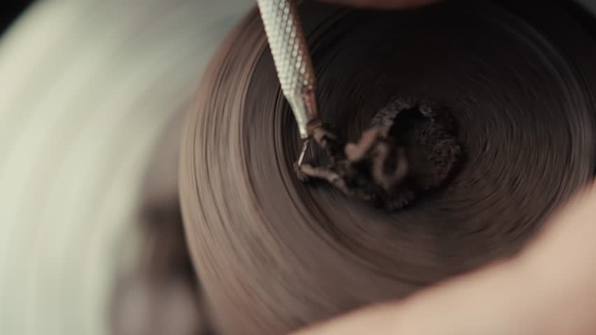 Potter's hands close up. The master makes the shape of a ceramic mug. Creative process. Making dishes from black clay on a potter's wheel.