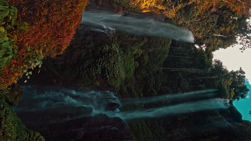 Beautiful waterfall hidden in tropical rainforest jungle on nature background 4K vertical video