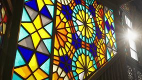 Multicolored stained glass vintage windows with patterns glow during the day, the camera slowly rises up the stairs with a ray of sun in the gap in a historic building or church, vintage front - Powered by Shutterstock - Get 15% off with code: PIKWIZARD15