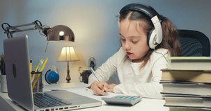 Happy Little Female Student Wearing Distance Learning School Headphones, Studying Online in Virtual Classroom With Tutor Teacher Via Videoconference, Watching Lesson on Laptop at Home, Classroom.