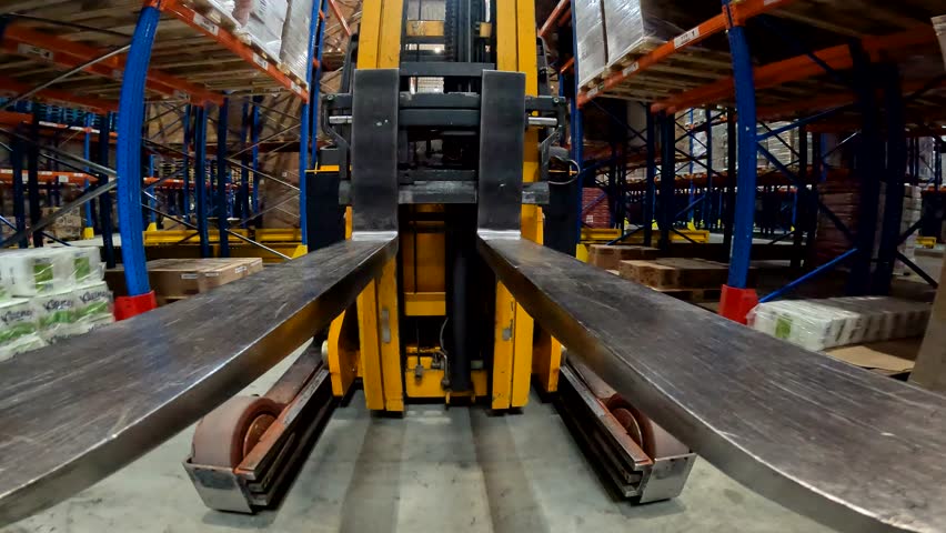 The load lifter rides on the warehouse pov. Forklift fork close-up. Modern forklift in a large warehouse Royalty-Free Stock Footage #1103531609