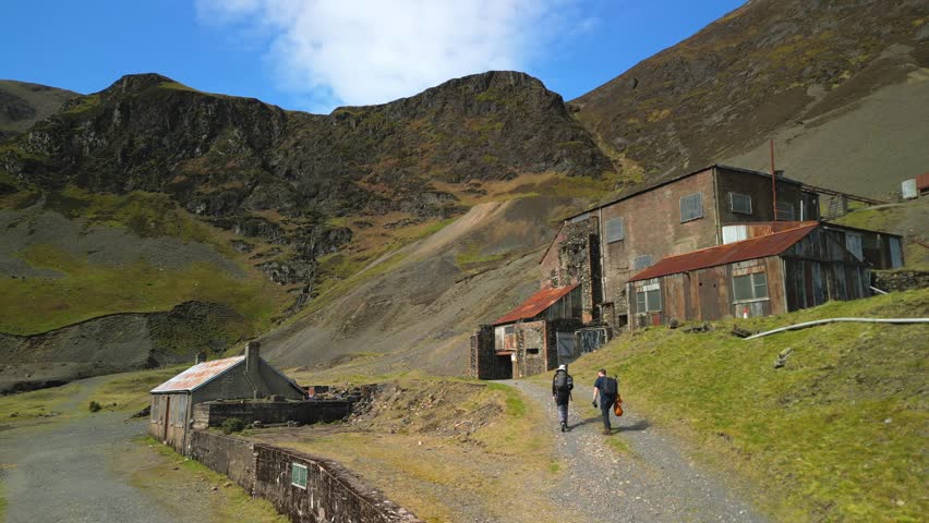 Hikers walking up to derelict mine works at Coledale Beck in the English Lake District Cumbria