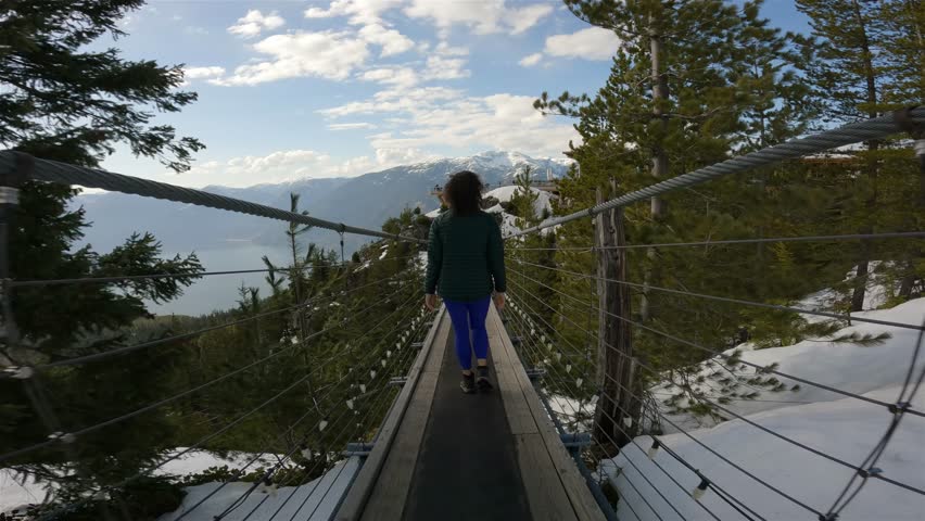 Woman walking on Suspension Bridge in Canadian Nature. Squamish, British Columbia, Canada. Sunny Spring Season Day.