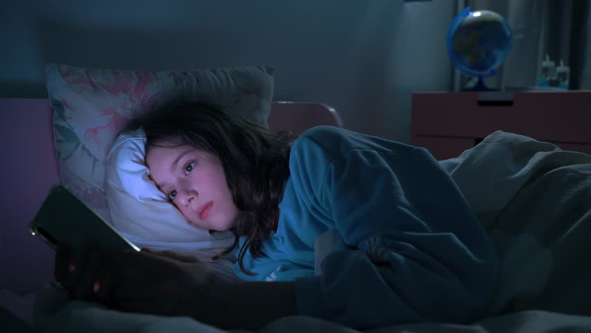 Teen girl lying in bed at night using smartphone, scrolling social media and texting. Not healthy sleep. Insomnia and the harm of the smartphone before going to bed. Dependence on social networks Royalty-Free Stock Footage #1103537047
