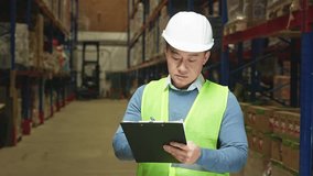 Experienced warehouse manager in white hardhat and reflective vest writing down on clipboard while inspecting supplies. Asian mature man having regular revision to control logistics. - Powered by Shutterstock - Get 15% off with code: PIKWIZARD15