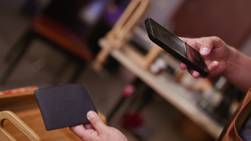 Person takes photo of simple men black leather wallet with cellphone in studio closeup. Master of manual manufacture shows product online