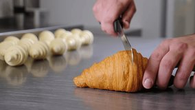 Cutting croissant with knife. Close up view. puff pastry bakery product. Delicious fresh french croissant. confectionery production. Food industry manufacture 4 k video