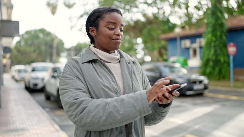 African american woman dancing listening to music on smartphone at street