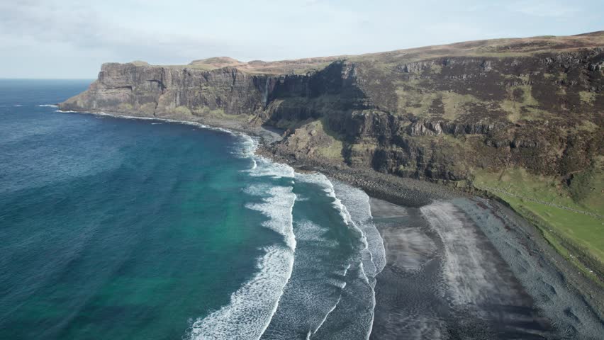 Large waves out the Atlantic ocean rooling on a gravel beach in Talisker Bay in Scotland. Drone dolley shot Royalty-Free Stock Footage #1103560731