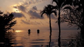 A video of a boy and a girl hanging out at the edge of the infinity pool during sunset in Thailand