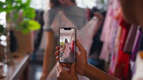 Two friends shopping for clothes in fashion store taking video of dress - shot in slow motion