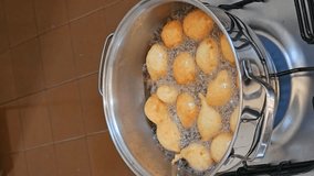 Frying the raincake, typical food in Brazil, fried dough in oil, 4k, vertical video, selective focus.
