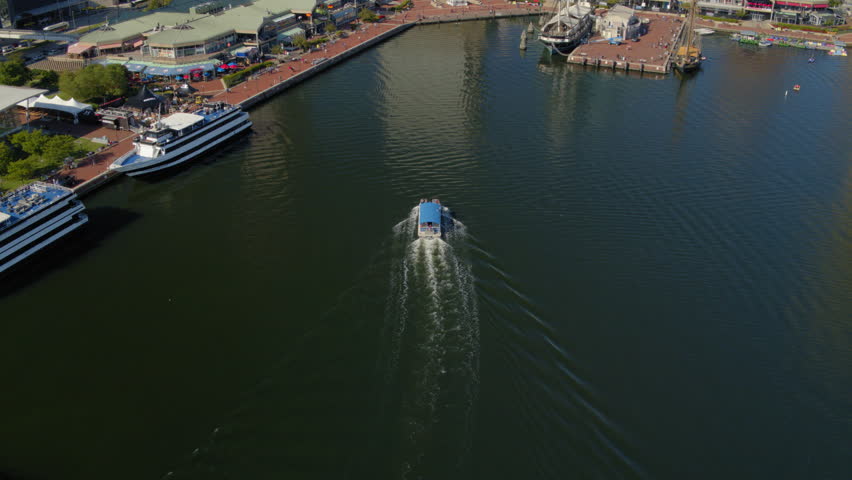 Aerial Tilt Up Shot Of Boats At River While City In Background During Sunny Day - Baltimore, Maryland