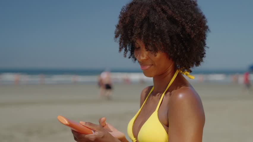 Close up of a happy smiling young black woman is applying a sunscreen or sun tanning lotion on a shoulder to take care of her skin on a seaside beach during holidays vacation.
 Royalty-Free Stock Footage #1103576033