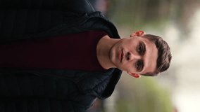 Vertical video, portrait of a handsome young male model, wearing casual clothes, looking in camera, neutral look, outdoors - Powered by Shutterstock - Get 15% off with code: PIKWIZARD15