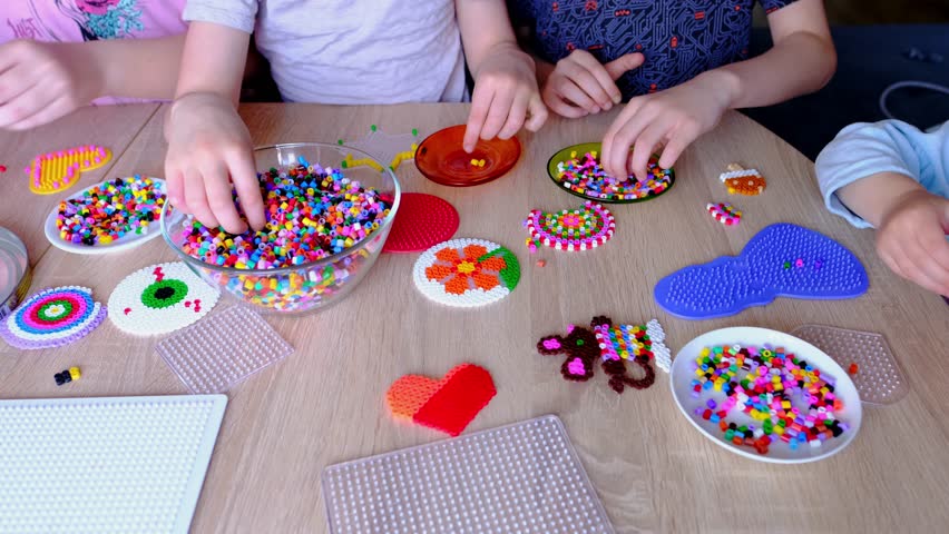 close-up of children's hands creating perler bead patterns, make crafts using thermomosaic technique, beading patterns, perler bead art, concept development of fine motor skills, thermo mosaic ideas Royalty-Free Stock Footage #1103577341