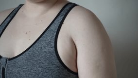 Light-skinned young woman with drooping arms. Sad bad body shape girl. fat on the arms, not inflated biceps, sagging skin. 4k video. Fat, fat arms with excess weight.