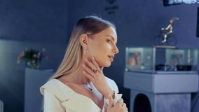 Charming beautiful model tries on a diamond necklace elegantly posing in mirror in a jewelry store. Girl is decorated with gold jewelry, earrings, gold rings in a luxury boutique. Wedding day. - Powered by Shutterstock - Get 15% off with code: PIKWIZARD15