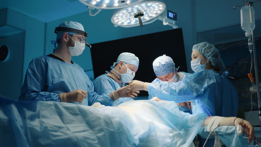 Process of plastic surgery procedure performed in modern operating room with led operation theatre light, monitor. Surgical team consists of four people. High quality 4k footage Royalty-Free Stock Footage #1103582813