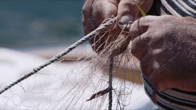 Fisherman is Repairing Fishnets on Fishing Boat in Dock  Video